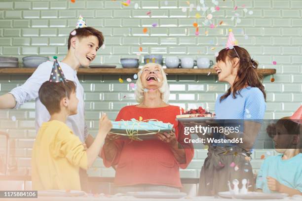 mother and sons celebrating grandmother's bithday in their kitchen - older woman birthday stock pictures, royalty-free photos & images