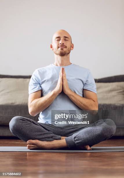 man doing yoga at home - lotuspositie stockfoto's en -beelden