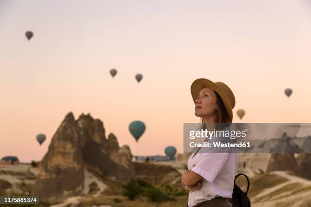 young woman and hot air ballons, goreme, cappadocia, turkey - cappadocia hot air balloon stock-fotos und bilder