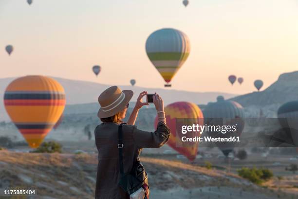 young woman and hot air ballons, goreme, cappadocia, turkey - hot air balloon people stock pictures, royalty-free photos & images
