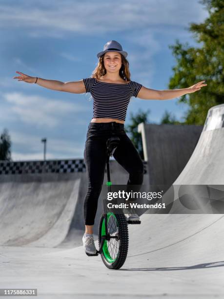 young woman riding unicycle in skatepark - unicycle stock pictures, royalty-free photos & images