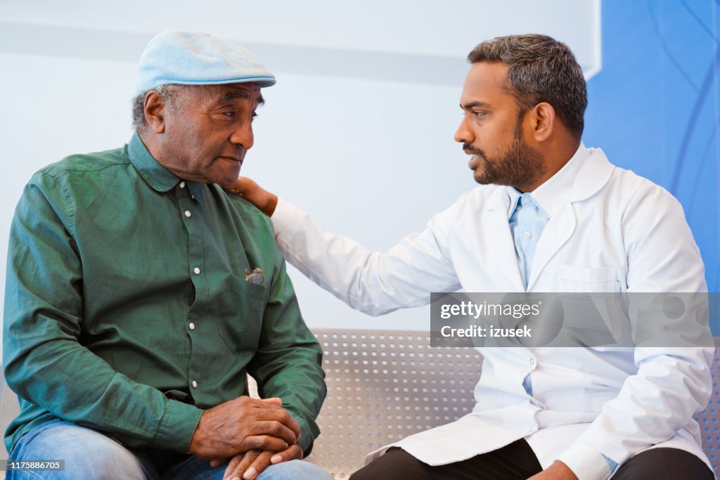 Doutor masculino que consolando o paciente sênior no hospital