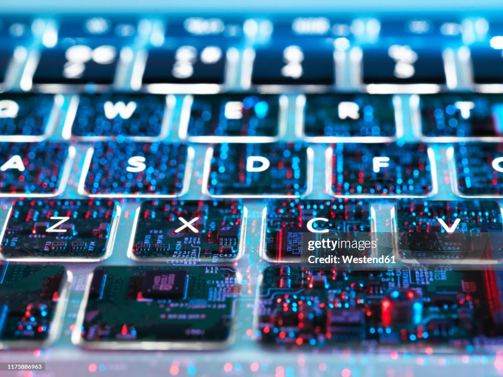 Double exposure of a laptop computer showing electronic components under the keyboard