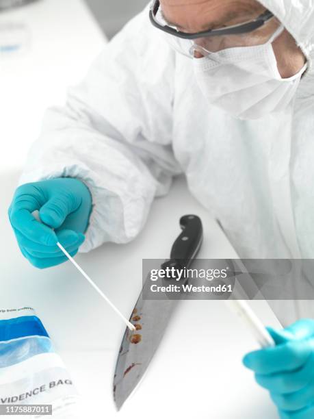 forensic scientist taking dna evidence from a blood smeared knife - evidence bag stock pictures, royalty-free photos & images