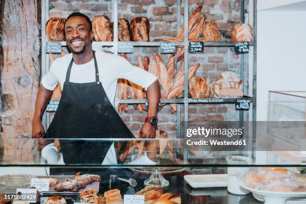 smiling man working in a bakery undressing his apron - bakery owner stock pictures, royalty-free photos & images