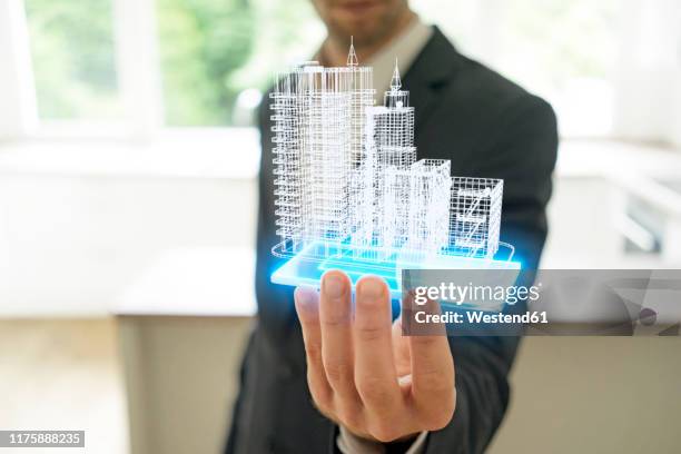 businessman holding hologram of architectural model - städtebaumodell stock-fotos und bilder