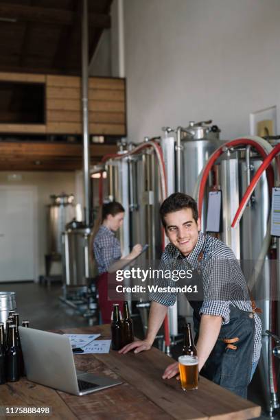 smiling young entrepreneur working at a brewery - thinktank stock pictures, royalty-free photos & images