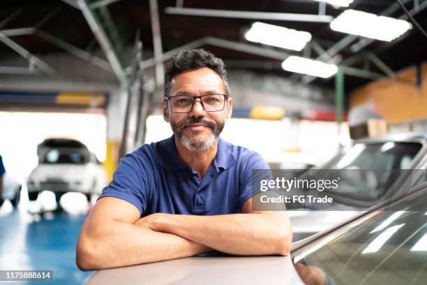 portret van een man met armen gekruist leunend in een auto repair shopon een auto - automotive technician stockfoto's en -beelden