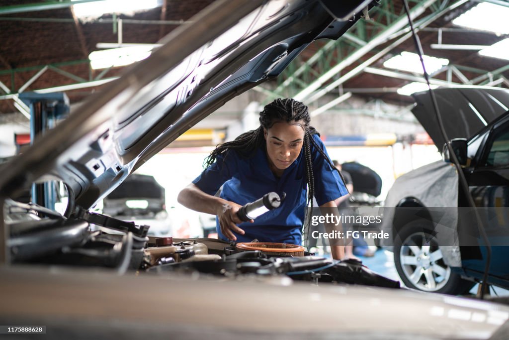 Woman repairing a car in auto repair shop