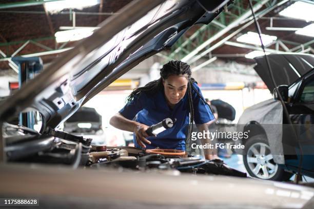 Woman repairing a car in auto repair shop