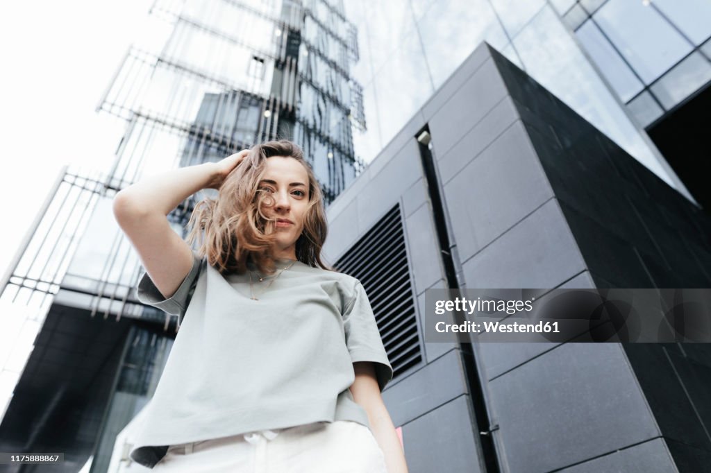 Portrait of smiling woman looking at camera, modern office buildings in the background, low angle view