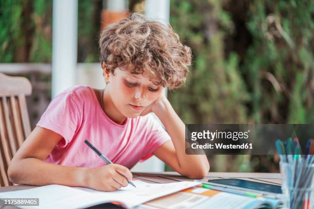 boy sitting at garden table doing homework - välklädd bildbanksfoton och bilder