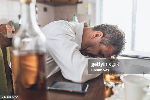 een bejaarde man misbruikt alcohol - hangover stockfoto's en -beelden