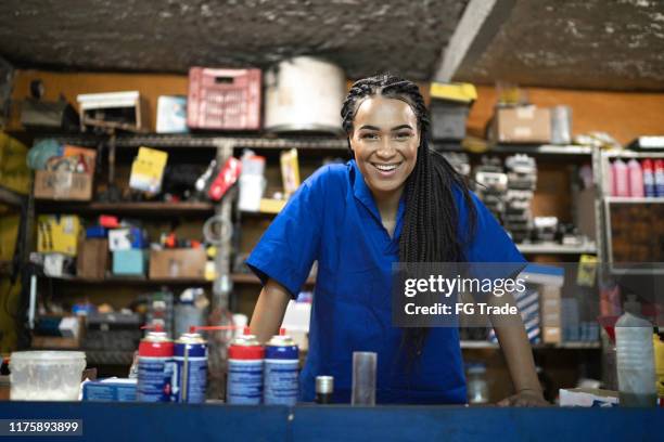 portrait of a female mechanic standing behind de counter in a auto repair shop - small car stock pictures, royalty-free photos & images