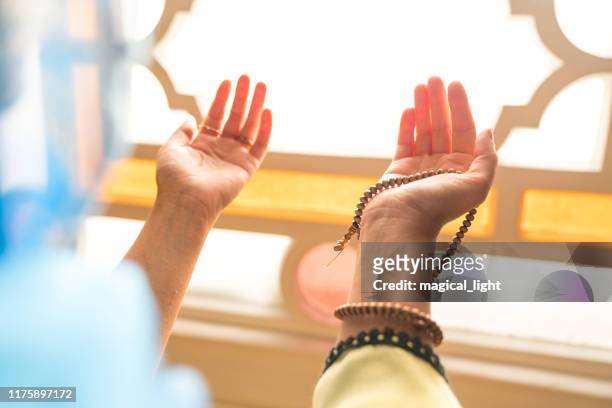 muslimische frau in kopftuch und hijab betet mit den händen in der luft in der moschee. religion beten konzept. - islam stock-fotos und bilder
