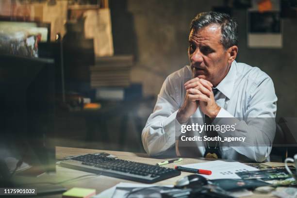 detective trabajando de noche en la oficina - jefe de policía fotografías e imágenes de stock