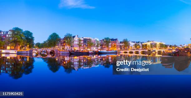 panoramisch uitzicht op de brug van de magere brug en grachtenpanden aan de amstel bij twilight, amsterdam, nederland - magere brug stockfoto's en -beelden