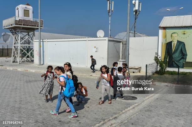 Syrian students walk past a poster of Turkish president Recep Tayyip Erdogan at the Boynuyogun refugee camp on September 16, 2019 in Hatay, Turkey....