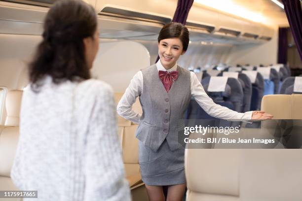 chinese flight attendant showing seats on plane - first class plane stock-fotos und bilder