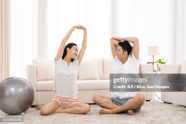 young chinese couple exercising in living room - asian man barefoot foto e immagini stock