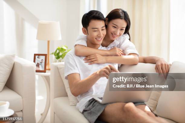 young chinese couple using laptop at home - asian young couple stock pictures, royalty-free photos & images