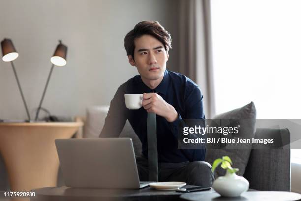 young chinese businessman drinking coffee in hotel room - asian man suite stock-fotos und bilder