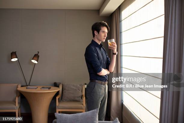 young chinese businessman drinking alcohol in front of window - wealthy asian man stock pictures, royalty-free photos & images