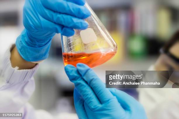 laboratory concept; blurred picture scientist is looking the reaction of reagent in flask at laboratory - organic chemistry in laboratory fotografías e imágenes de stock