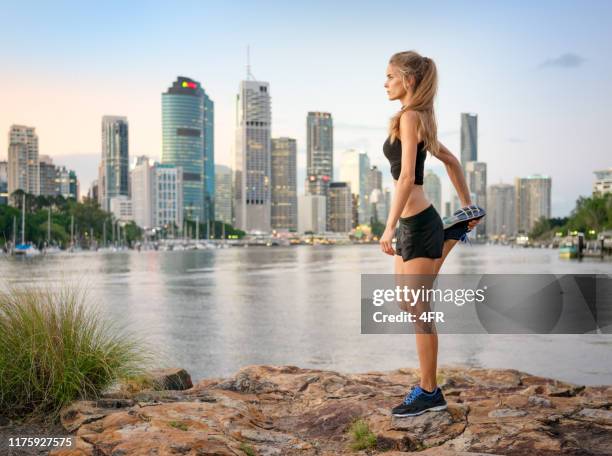 athletic woman stretching, brisbane skyline, australien - brisbane stock-fotos und bilder