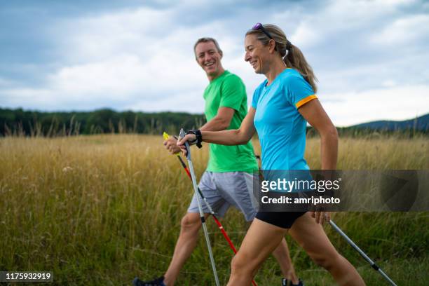 happy mature adult nordic walkers - hiking pole stock pictures, royalty-free photos & images