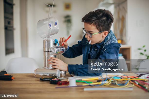 jongen maken robot speelgoed van recycling materiaal - child with robot stockfoto's en -beelden