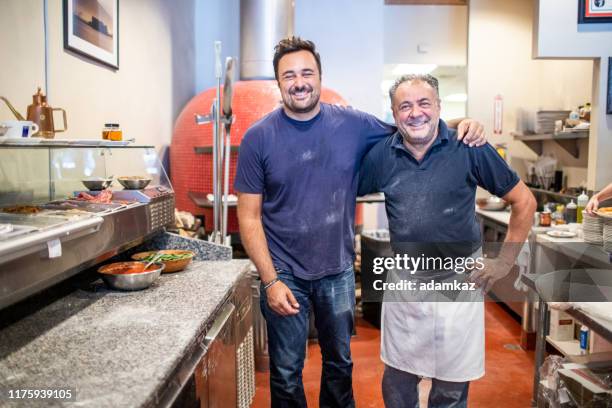 vater und sohn in ihrer pizzeria - italienischer abstammung stock-fotos und bilder