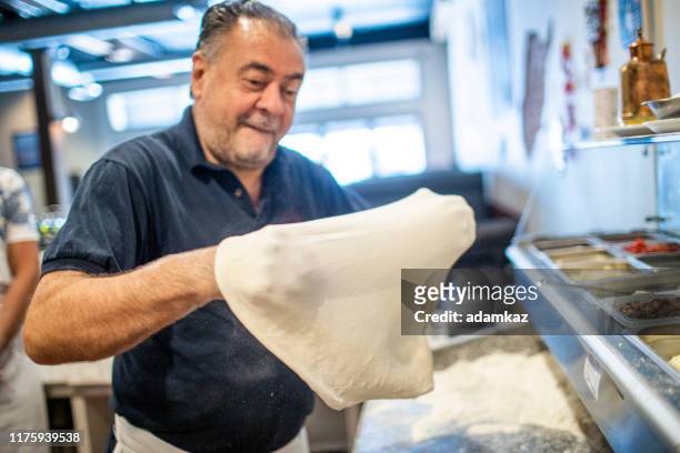 senior italian man working pizza dough - pizza toss foto e immagini stock