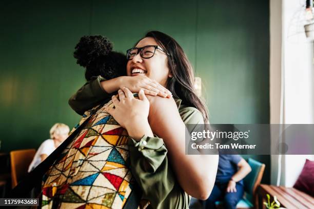 two friends hugging in cafe - indonesische etniciteit stockfoto's en -beelden