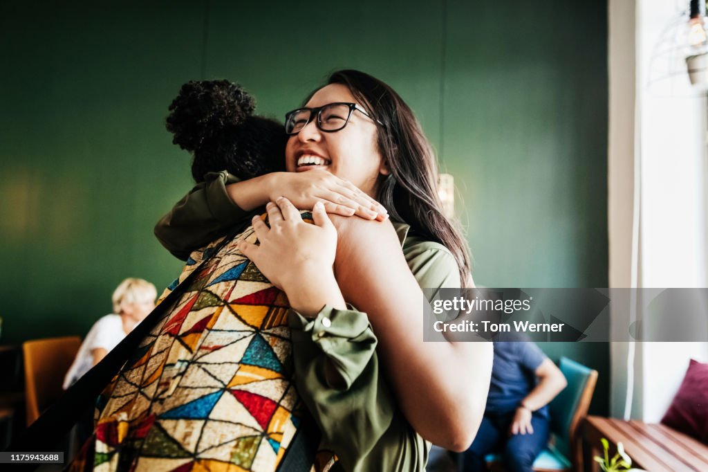 Two Friends Hugging In Cafe