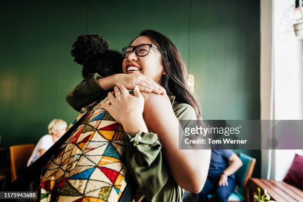 two friends hugging in cafe - embracing stock pictures, royalty-free photos & images