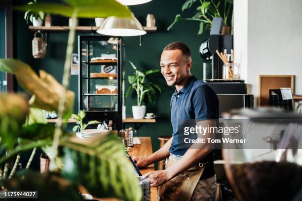 barista at work behind counter in cafe - bar man t shirt stock-fotos und bilder
