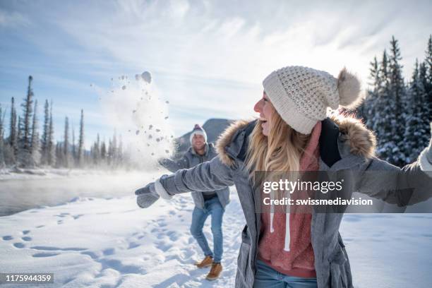 playful couple snowball fighting in winter - banff snow stock pictures, royalty-free photos & images