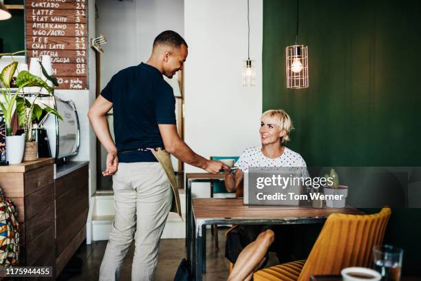 woman receiving coffee she ordered at cafe - women serving coffee stock-fotos und bilder