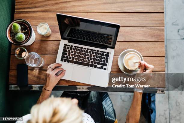 aerial view of woman using laptop and drinking coffee - draufsicht tisch stock-fotos und bilder