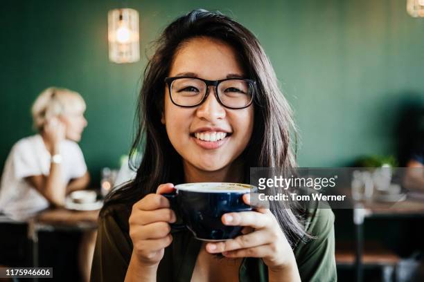 portrait of young woman smiling drinking coffee - café bebida fotografías e imágenes de stock