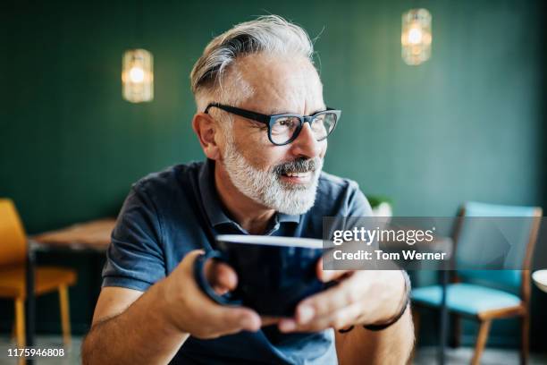 cafe regular customer sitting down drinking coffee - bel homme 55 ans photos et images de collection