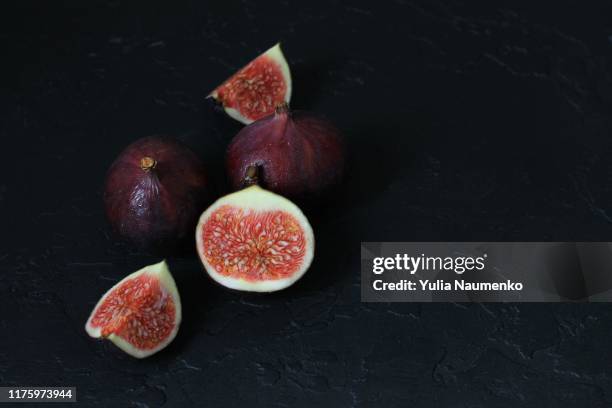 close up of well ripened figs, cut open to expose seeds and juicy innards. still life composition on black background. - food photography dark background blue stock pictures, royalty-free photos & images