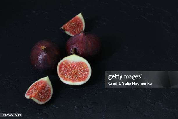 close up of well ripened figs, cut open to expose seeds and juicy innards. still life composition on black background. - food photography dark background blue imagens e fotografias de stock