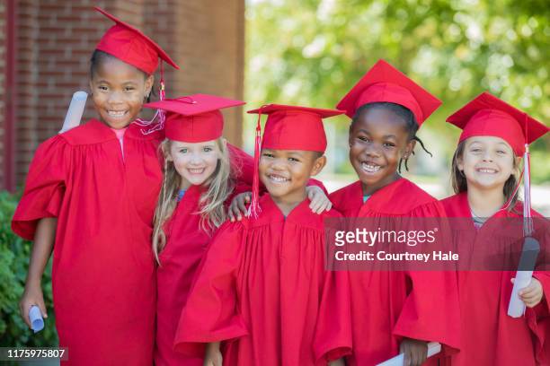 group of elementary age students at graduation ceremony - kids certificate stock pictures, royalty-free photos & images