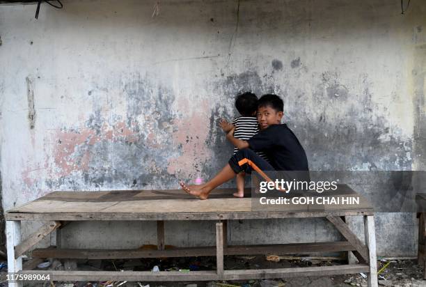 This picture taken on October 11, 2019 shows a boy playing with his brother in a neighbourhood in Jakarta. - A diet heavy on cheap, modern food like...