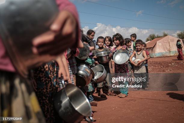 Children, holding bowls and pots, queue to receive food aid in Idlib, Syria on October 07, 2019. While more than 820 million people worldwide...