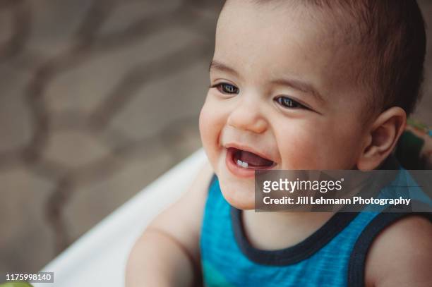 adorable and cute 10 month old baby boy sits in walker / bouncer and is teething - gezahnt stock-fotos und bilder
