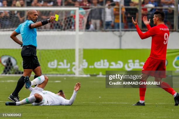 Omani referee Ahmed al-Kaf flashes a yellow card to Palestine's midfielder Tamer Seyam during the World Cup 2022 Asian qualifying match between...