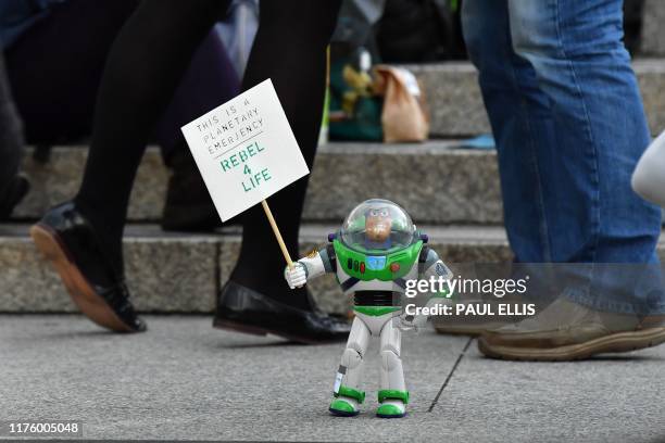 Buzz Lightyear toy from the Toy Story films is pictured holding a sign reading "Rebel 4 Life" as activists protest in Trafalgar Square during the...
